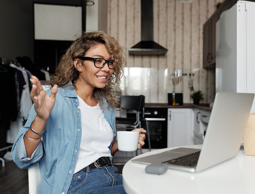 A woman joins an online lecture from her kitchen